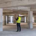 Ingegnere ispeziona pilastri e travi in cemento armato di un edificio esistente