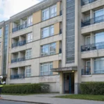 Edificio residenziale datato in cemento armato con un tecnico che consulta documenti