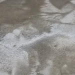 Velo biancastro di efflorescenze saline su una superficie in calcestruzzo