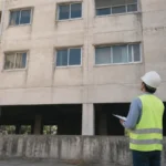 Ingegnere ispeziona la facciata in cemento armato di un edificio esistente